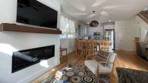 A modern living room with a flat-screen TV, fireplace, dining area, kitchen, and staircase. - 4-bedroom vacation home near Telluride Historic District (Telluride)
