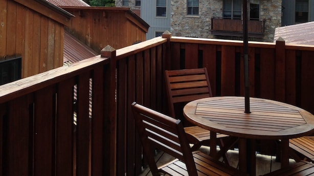 A wooden deck with a round table and chairs, an umbrella, and a view of a forested hillside. - 4-bedroom vacation home near Telluride Historic District (Telluride)