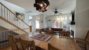 A dining area with a wooden table and chairs, a ceiling fan, and a staircase with a railing. - 4-bedroom vacation home near Telluride Historic District (Telluride)