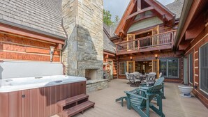 A hot tub, outdoor seating, and a stone fireplace. - Luxury Lodge on Private Mountain Top (Banner Elk)