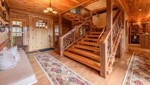 A wooden interior with a staircase, a sofa, and a rug. - Luxury Lodge on Private Mountain Top (Banner Elk)