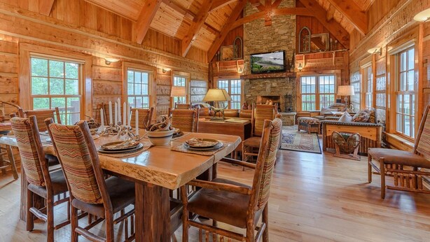A log cabin interior with a dining area, fireplace, and stone wall. - Luxury Lodge on Private Mountain Top (Banner Elk)