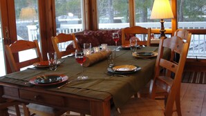 A wooden dining room with a table set for four, including wine glasses and plates. - AMAZING WATERFRONT SUNSETS ! (Ossipee)