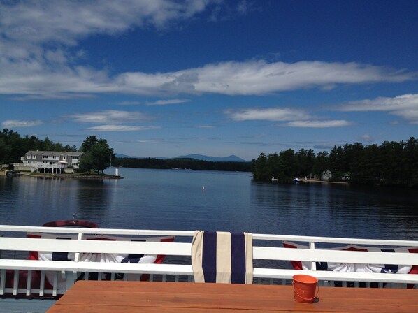 A lakeside view with a wooden deck and a table with a red bucket. - AMAZING WATERFRONT SUNSETS ! (Ossipee)