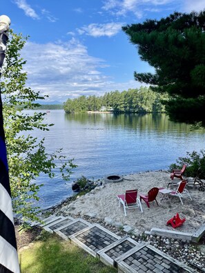A lakeside view with a deck, red chairs, and a fire pit. - AMAZING WATERFRONT SUNSETS ! (Ossipee)