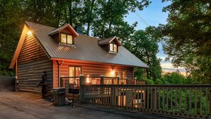 A log cabin with a metal roof, a deck, and a fenced area.