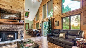 A cozy living room with a fireplace, leather sofa, and a foosball table.