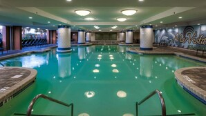 An indoor swimming pool with clear water, surrounded by lounge chairs and a mural on the wall.