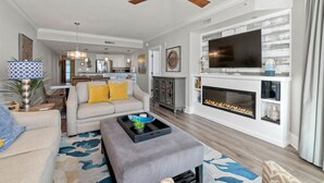 A living room with a fireplace, a ceiling fan, and a television mounted above it.