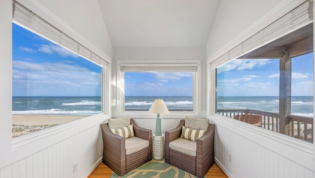 A room with a view of the ocean, wicker furniture, a lamp, and a patterned rug. - Oceanfront Dog Friendly Home w/ Hot Tub, Foosball, and Direct Beach Access (Avon)