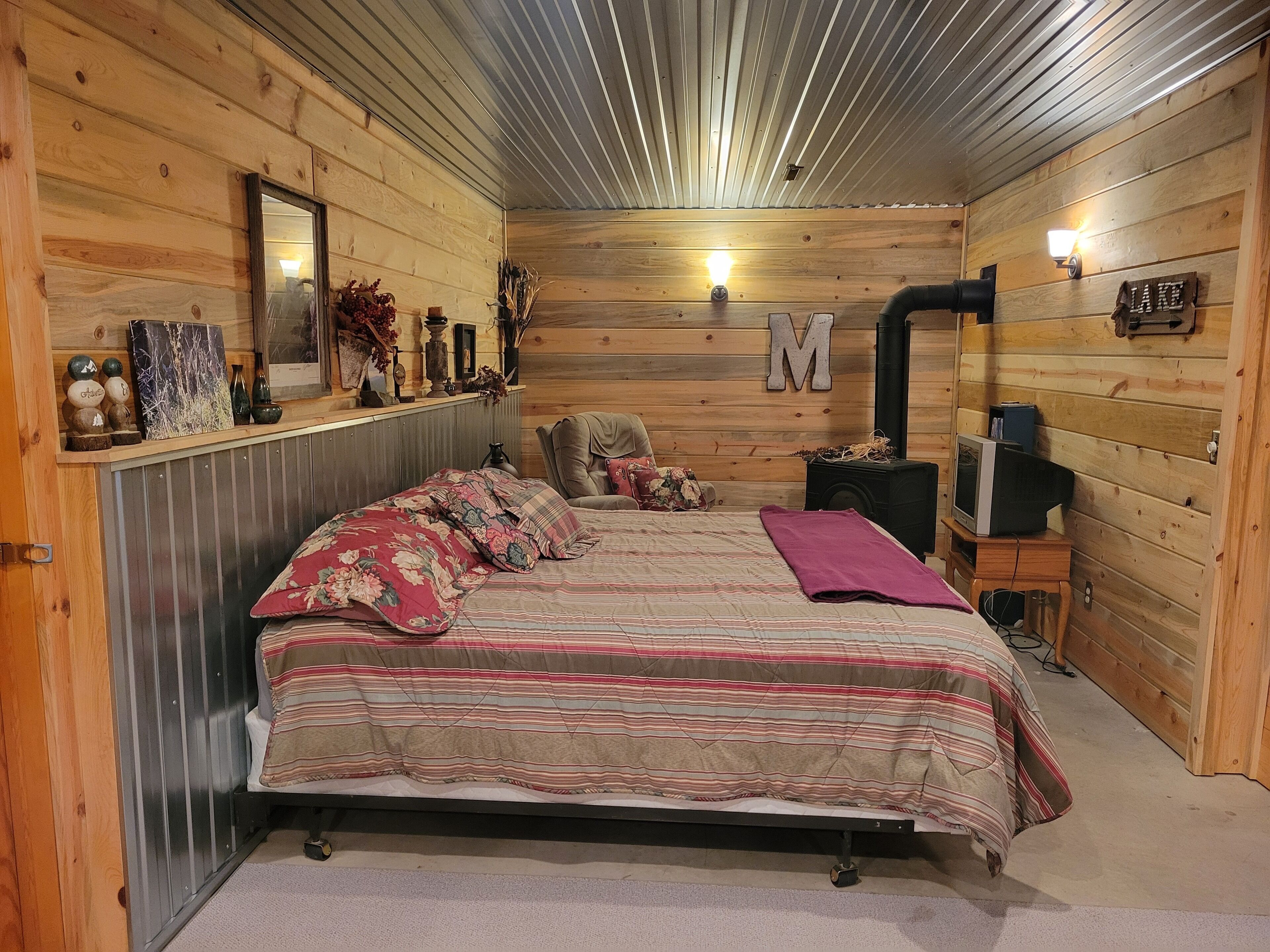 Um quarto acolhedor em estilo cabana, com cama, aquecedor, televisão e lareira.