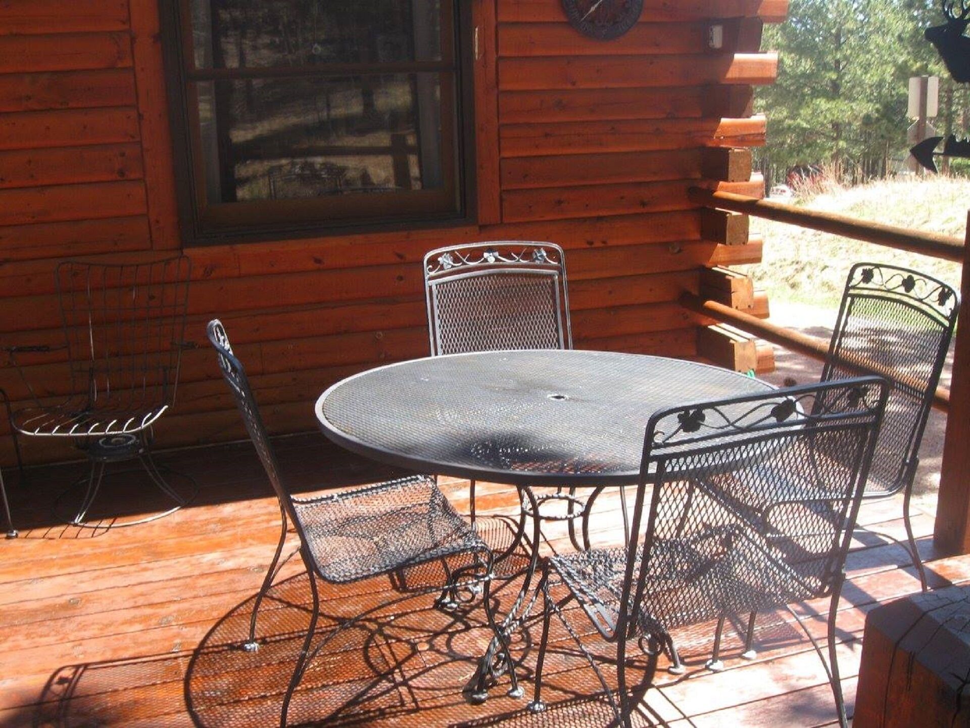 A wooden cabin with a metal table and chairs on the porch.