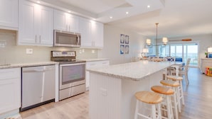 A modern kitchen with white cabinetry, stainless steel appliances, and a large island with bar stools. - Direct Gulf Front ! Completely Renovated Modern 2 Bedroom ! (Sanibel)