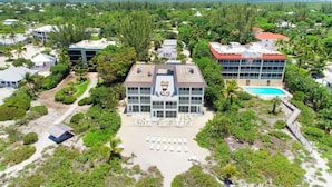 An aerial view of a resort with a central building, a pool, and surrounding greenery. - Direct Gulf Front ! Completely Renovated Modern 2 Bedroom ! (Sanibel)