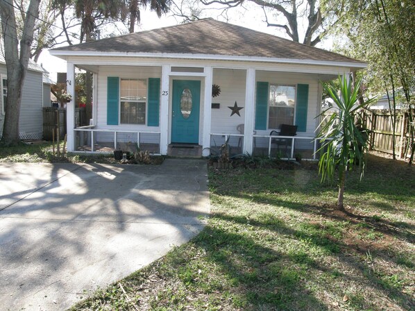 A single-story house with a front porch, a mailbox, and a small garden.