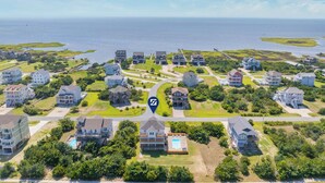 An aerial view of a coastal residential area with houses, a central road, and a body of water. - Soundside Dog Friendly Home w/ Pool, Hot Tub, Game Room, Community Boat Ramp (Salvo)