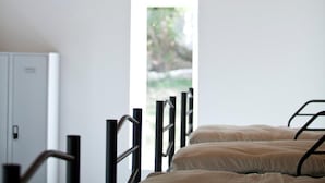 Une chambre avec un plafond en bois, un lit avec un cadre en métal et une fenêtre laissant entrer la lumière naturelle.