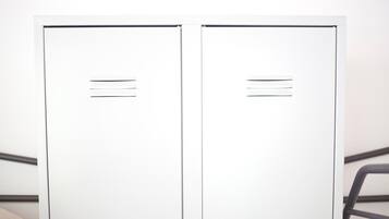 Dos taquillas metálicas blancas con líneas horizontales, probablemente para identificación, sobre un fondo uniforme.