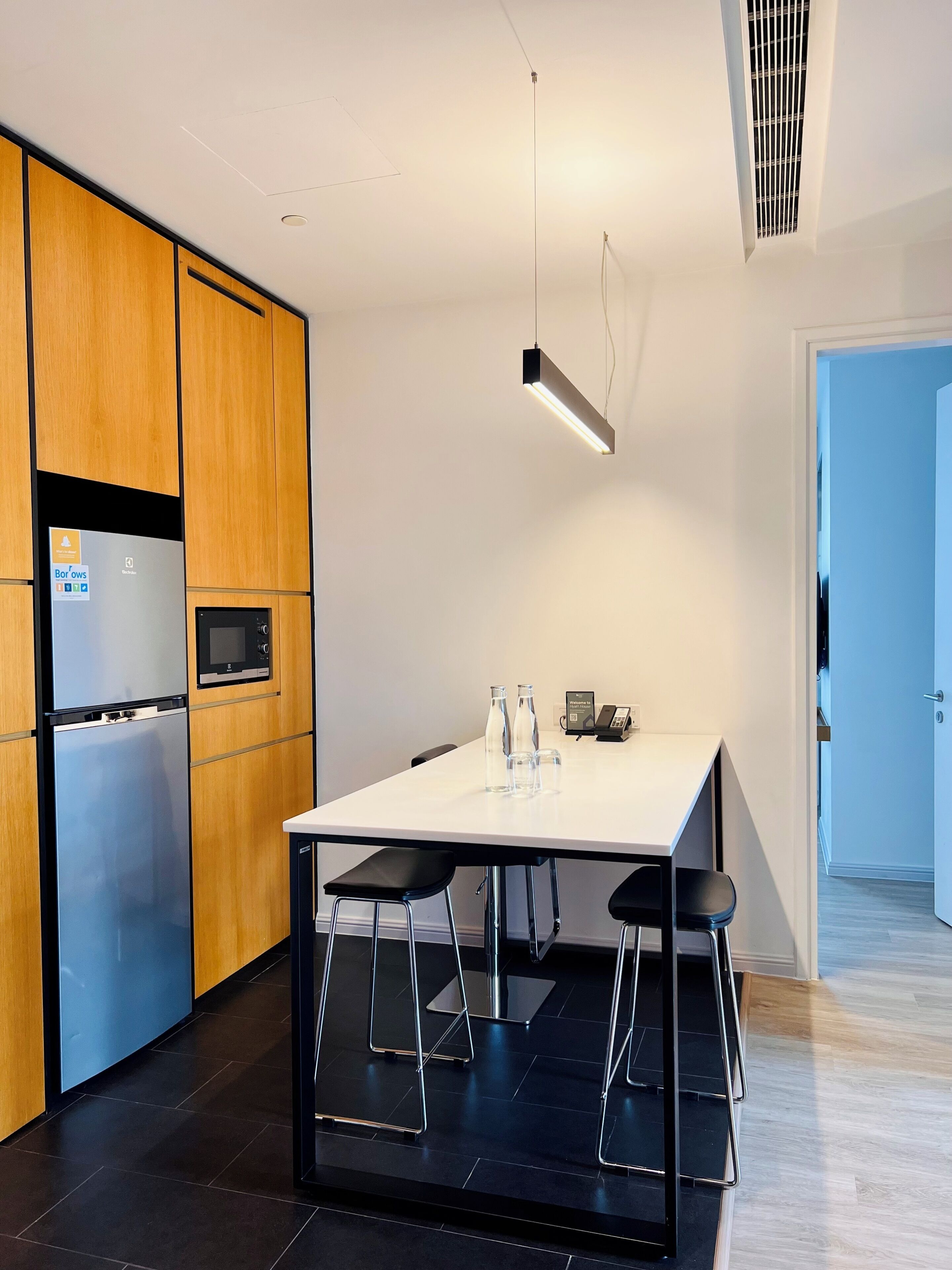 A modern kitchen with a white countertop, stainless steel appliances, and a black bar stool.