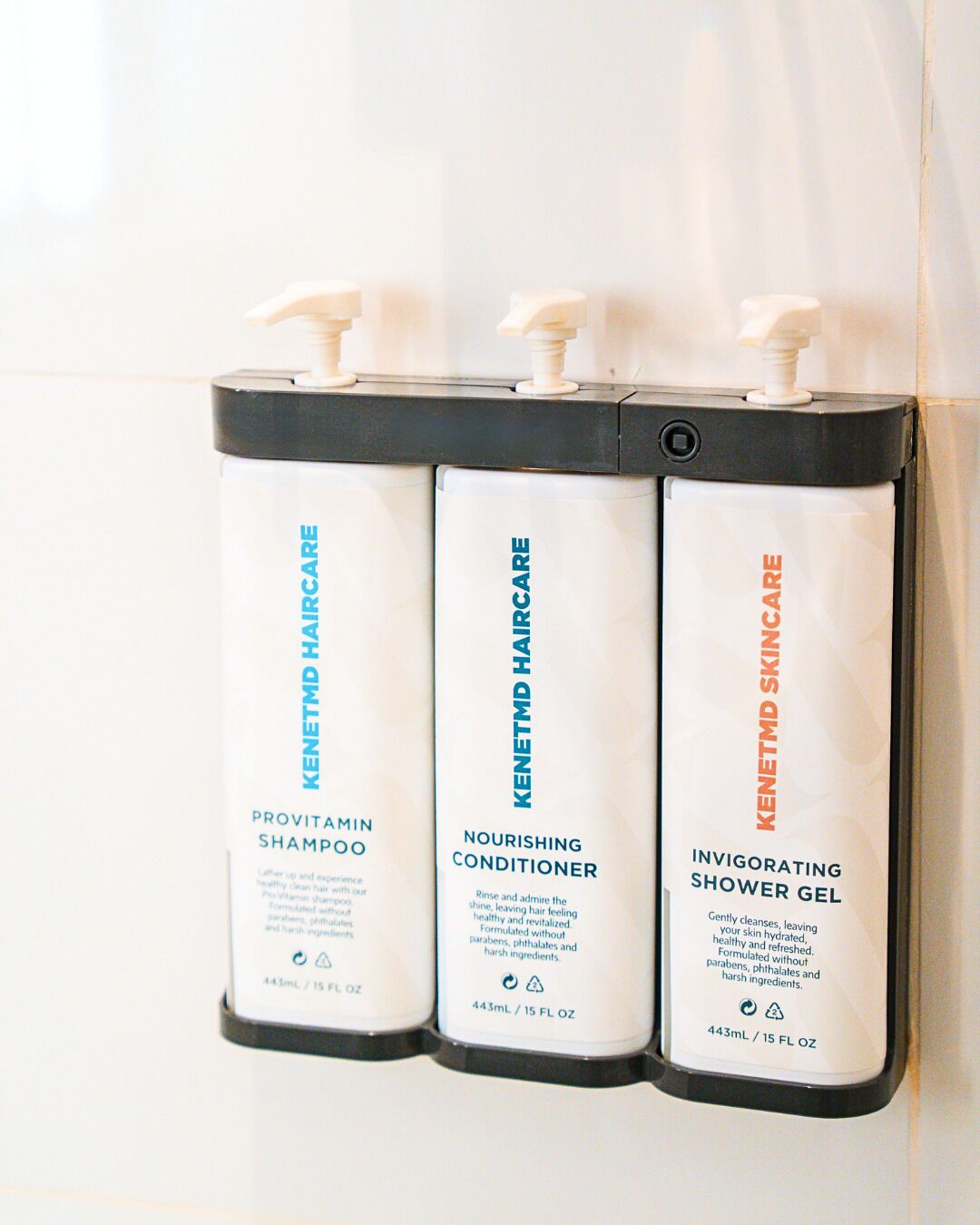 Trois flacons de produits de soins pour la peau sont posés sur un mur.