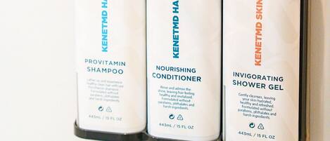Trois flacons de produits de soins pour la peau sont posés sur un mur.