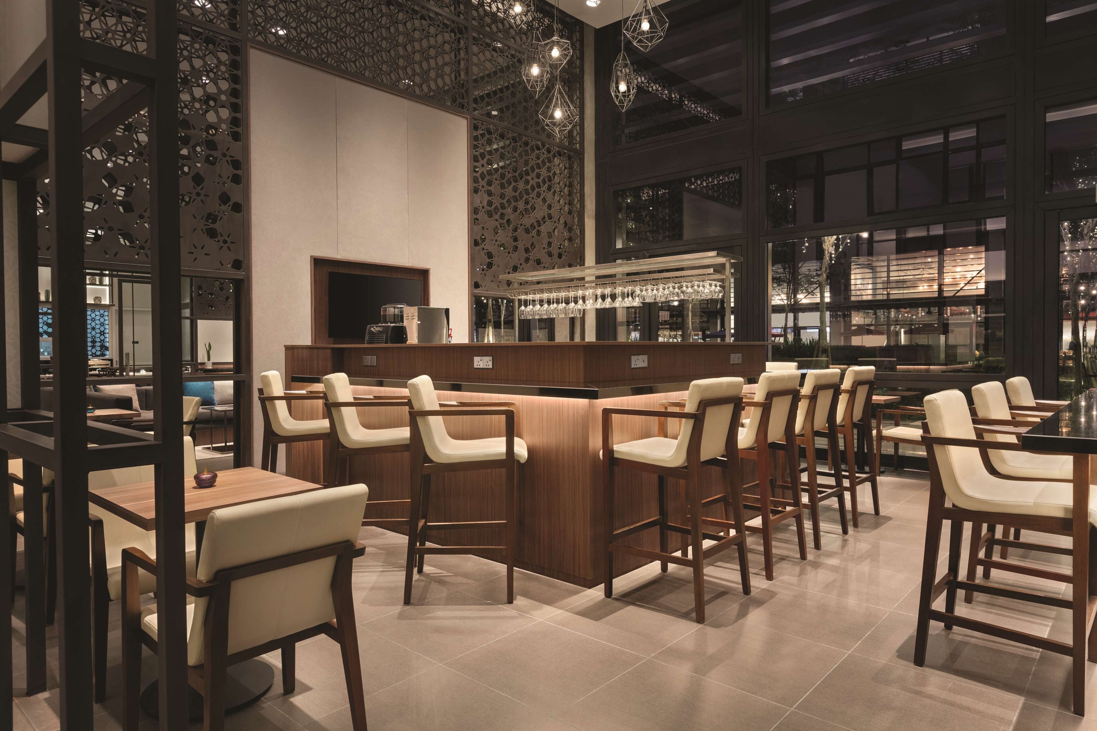 A modern bar area with high stools, a counter, and a decorative wall.