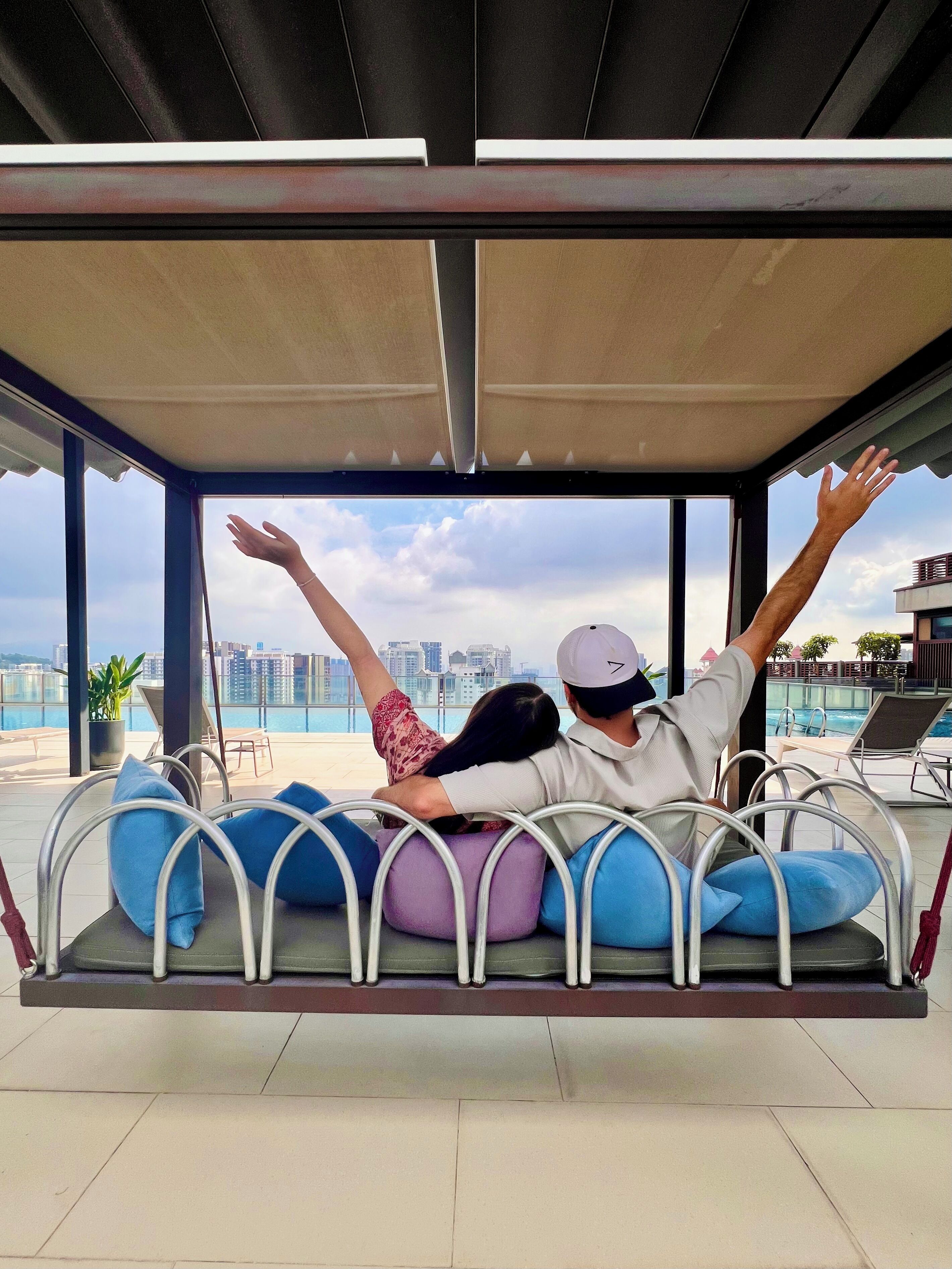 A couple relaxing on a swing chair with a city view.