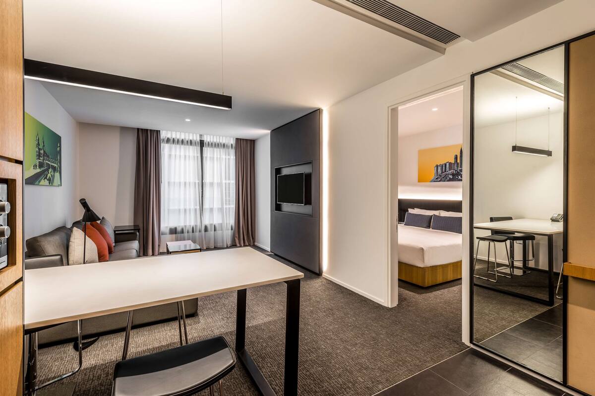 Una habitación de hotel moderna con una cama grande, un escritorio y una televisión.