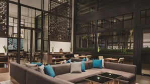 A modern interior with a sectional sofa, a coffee table, and a dining area with chairs and a table.