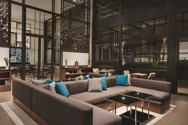 A modern interior with a sectional sofa, a coffee table, and a dining area with chairs and a table.