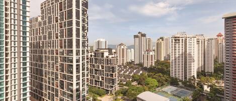 A high-rise residential building with multiple balconies, surrounded by greenery and other high-rise buildings.