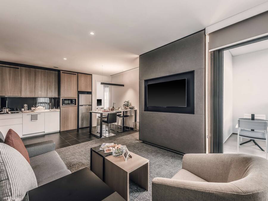 A modern living room with a sofa, coffee table, and a TV mounted on the wall.