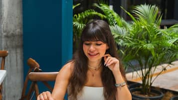 Una persona sentada en una mesa al aire libre con un plato de comida, un cartel de Hyatt House y plantas en macetas al fondo.