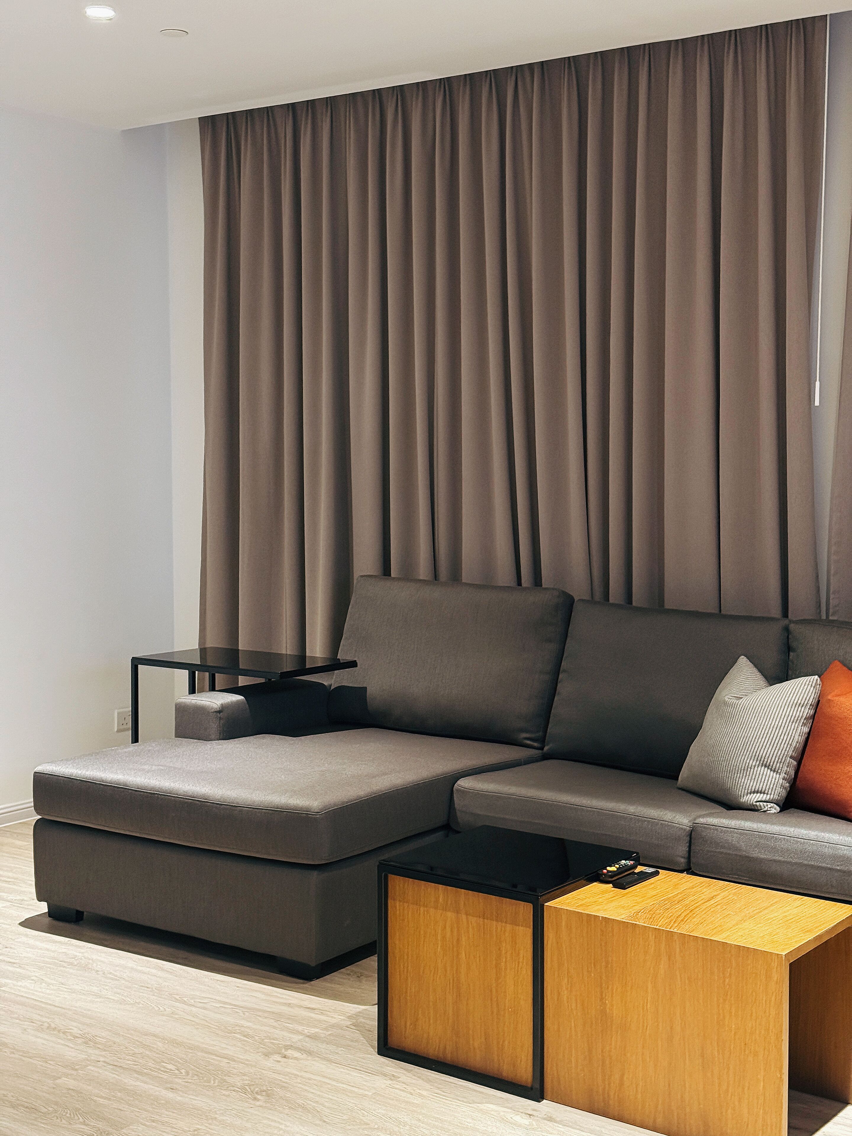 Un salon moderne avec un canapé d’angle, une table basse et une table d’appoint.