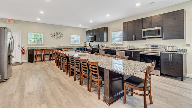 A spacious kitchen with a long island, dark cabinetry, and modern appliances. - GREAT FOR GROUPS! LUXURY PRIVATE POOL+SPA, GATHERING SPACES, AMAZING LOCATION (North Myrtle Beach)