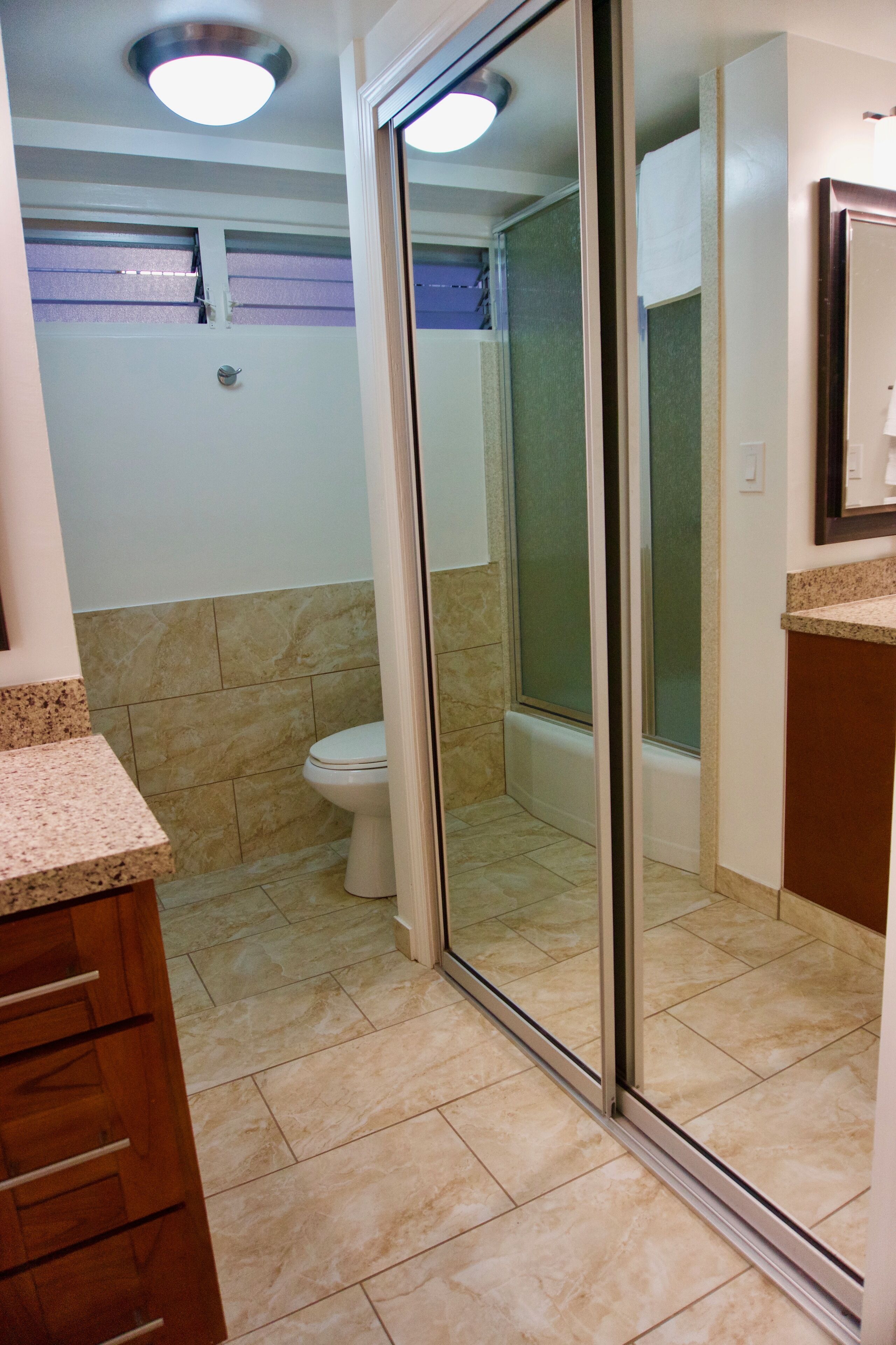 A bathroom with a toilet, a shower with a glass door, and a vanity with a granite countertop.