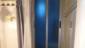 A bathroom with a toilet, a shower, and a window. - Pensión Santa María (Portugalete)