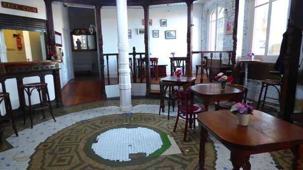 A traditional interior with wooden furniture, a patterned floor, and framed pictures on the walls. - Pensión Santa María (Portugalete)