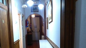 A narrow hallway with wooden floors, a white bench, and a ceiling light fixture. - Pensión Santa María (Portugalete)