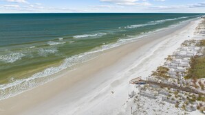 A beach with a long stretch of sand and a series of wooden walkways leading to a building.