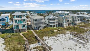 A beachfront resort with multi-story buildings, wooden walkways, and a view of the ocean.