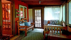 A cozy cabin interior with a wooden bench, a small table, and a door leading outside. - Cottage on the Kennebec (Caratunk)