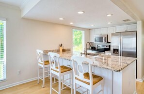 A kitchen with white cabinets, a marble countertop, and stainless steel appliances.