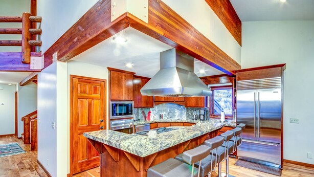 Una cocina amplia con una isla grande, electrodomésticos de acero inoxidable y detalles de madera.