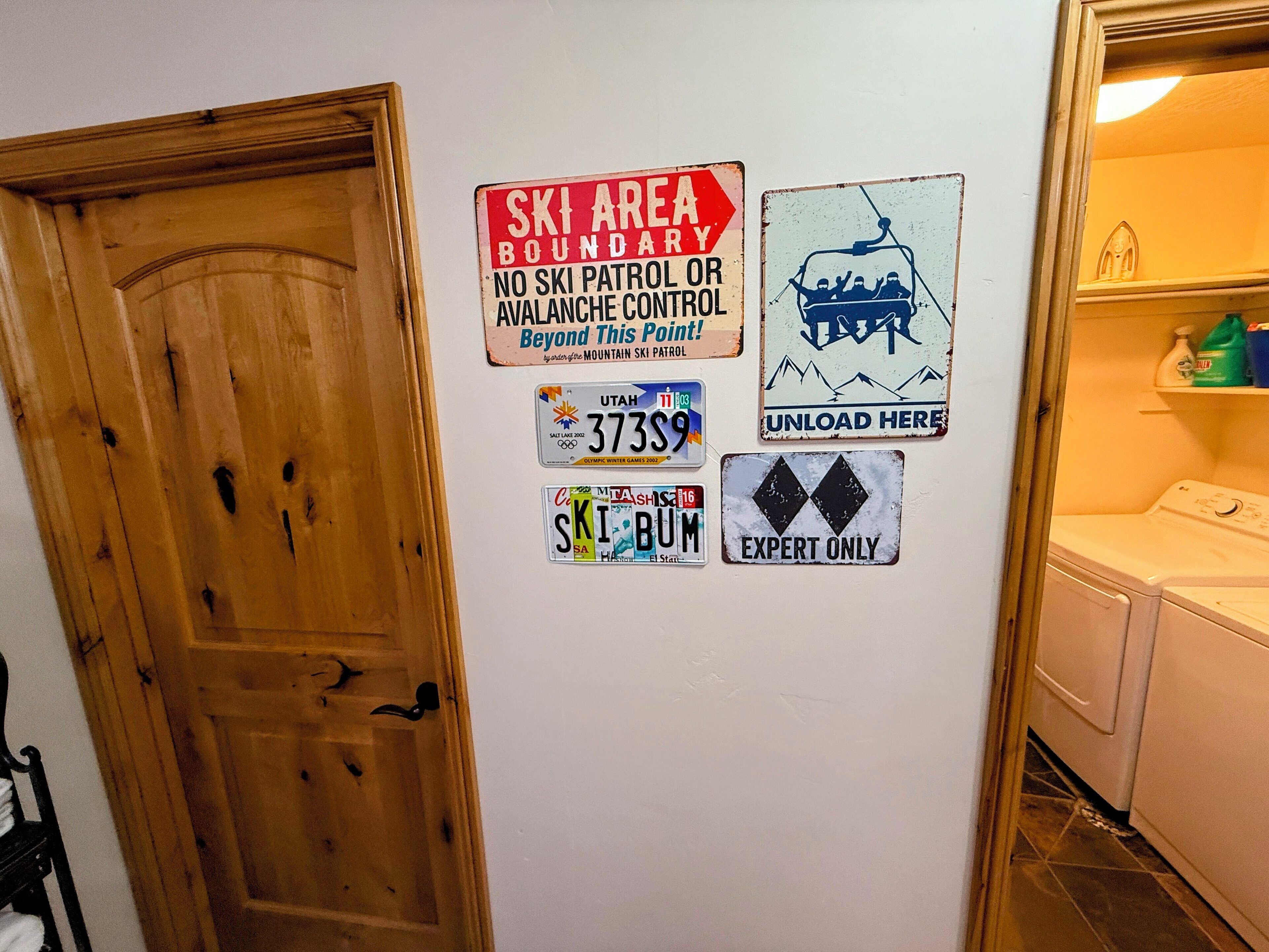 Una pared con varios carteles y placas de matrícula, incluyendo un letrero delimitador de área de esquí y una placa de Utah.