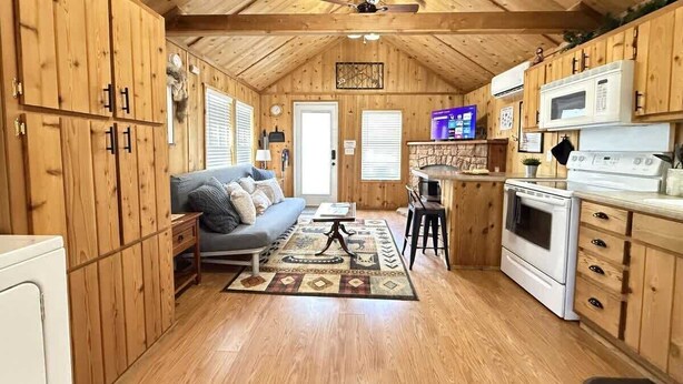 Un intérieur de chalet chaleureux avec des murs en bois, un coin cuisine, un canapé et un espace repas.