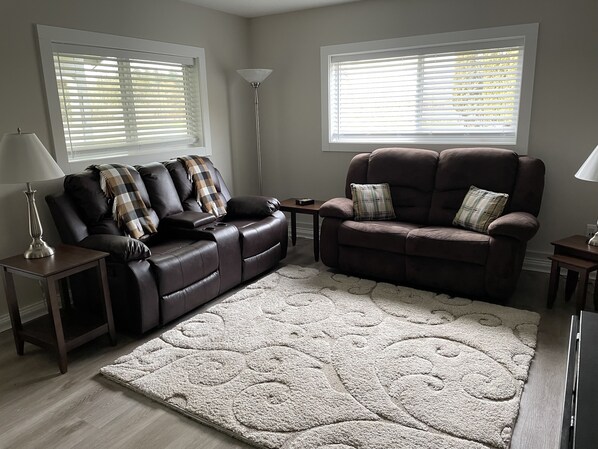 A living room with a brown leather sofa, a matching armchair, a small table, and a floor lamp. - NEW LISTING - Blueberry acres in Fort Langley (Langley)