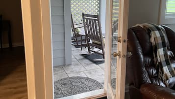 An open door leading to a patio with a table and chairs, a leather sofa, and a patterned rug.