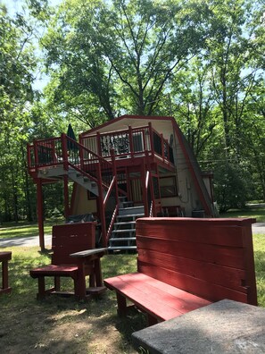 Un parc avec un escalier en bois rouge menant à une zone abritée, des bancs et une table de pique-nique.
