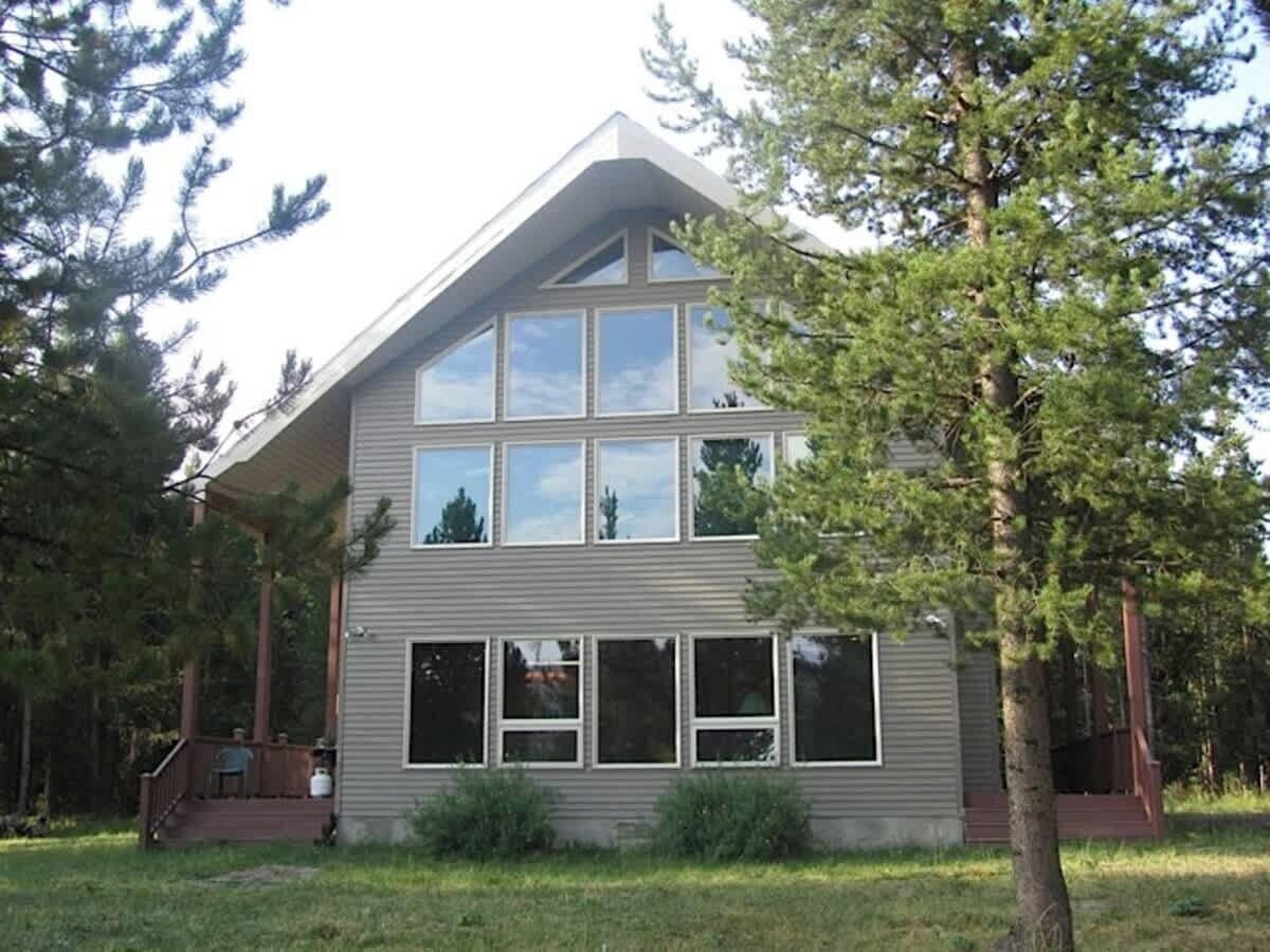 A two-story house with a sloped roof, large windows, and a porch.